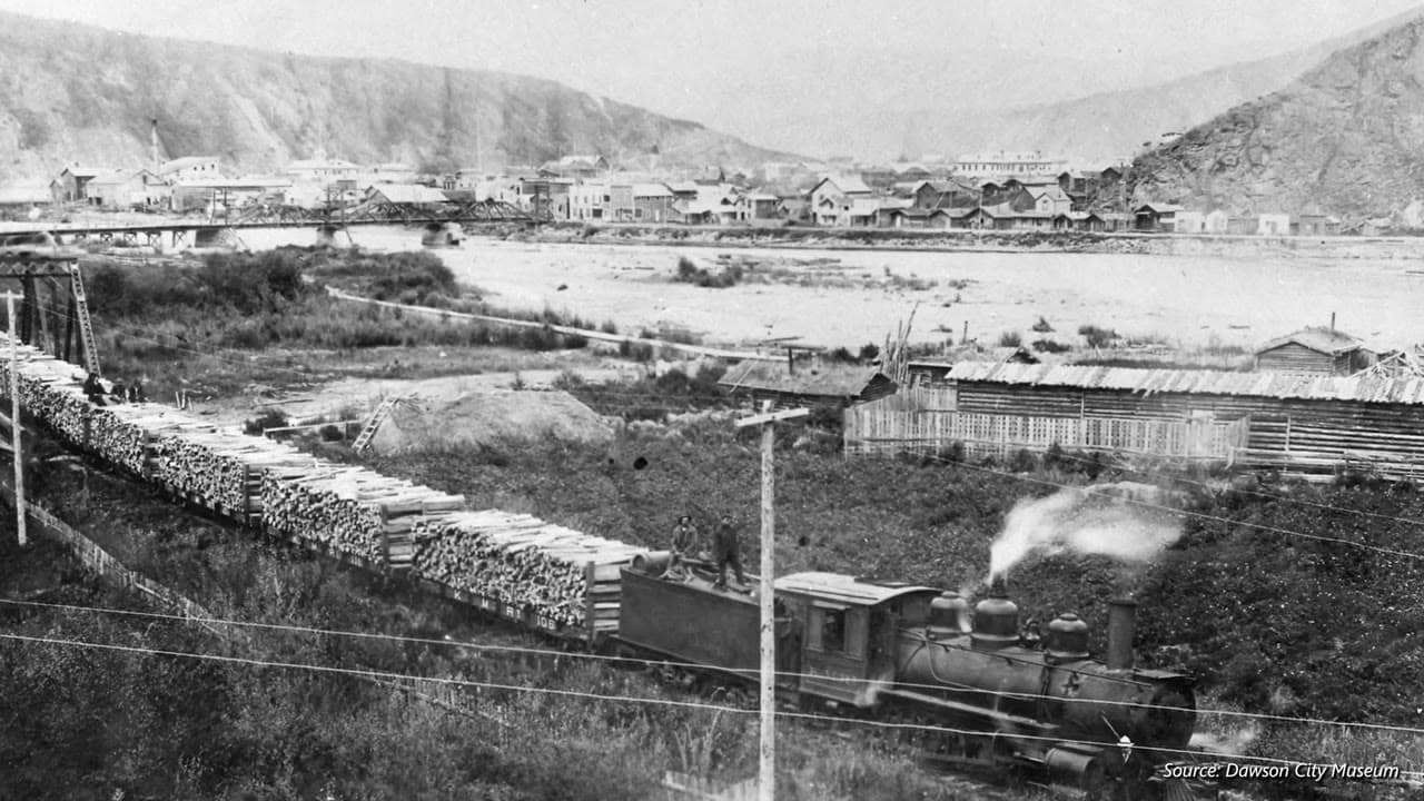 Dawson City Museum archival plate — steam logging train along the river town