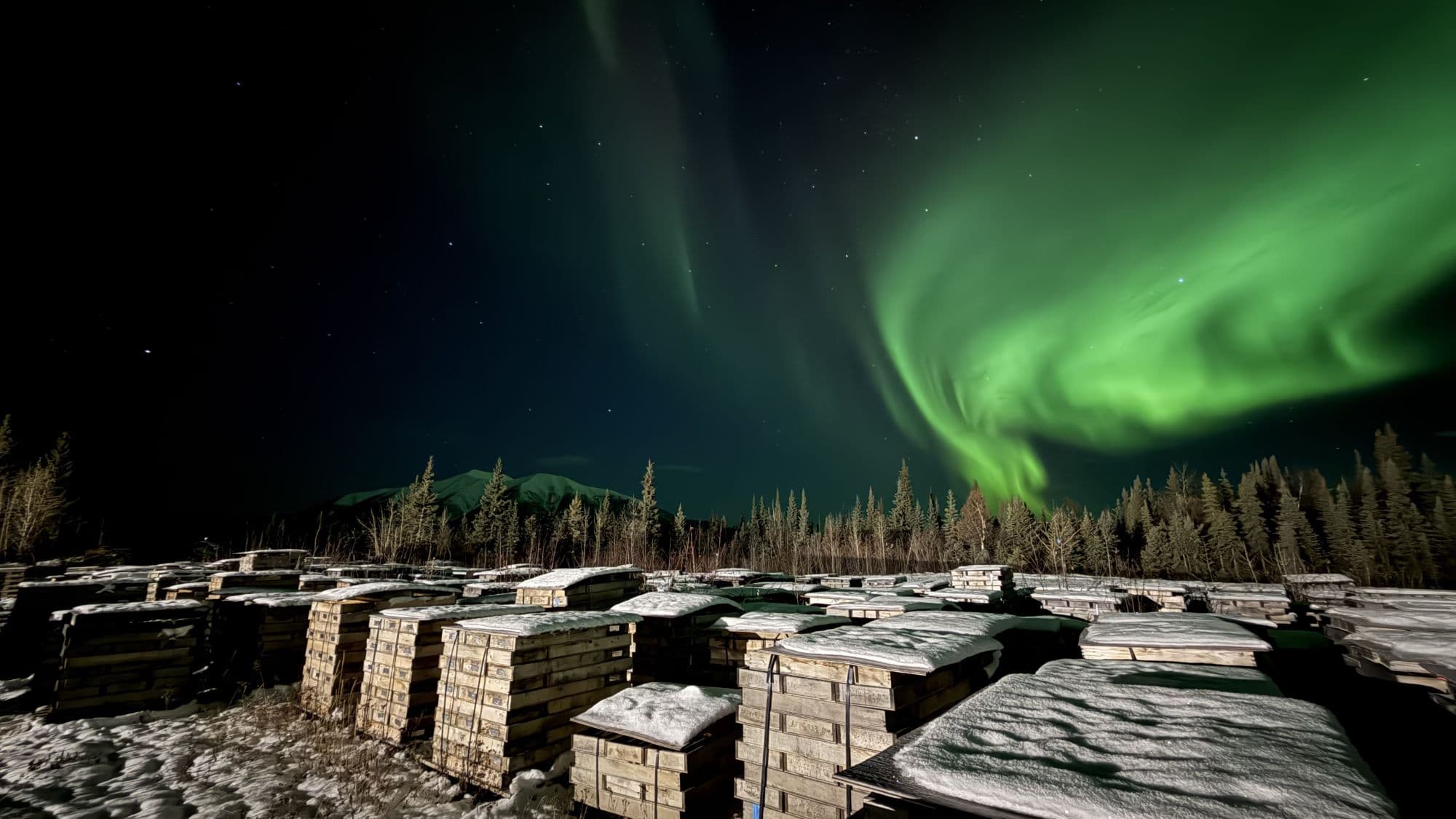 Northern lights over Mount Haldane and a Yukon field camp of stacked core boxes